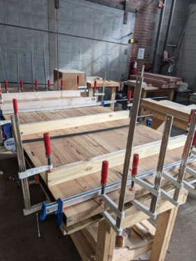 table top being clamped and glued together in workshop